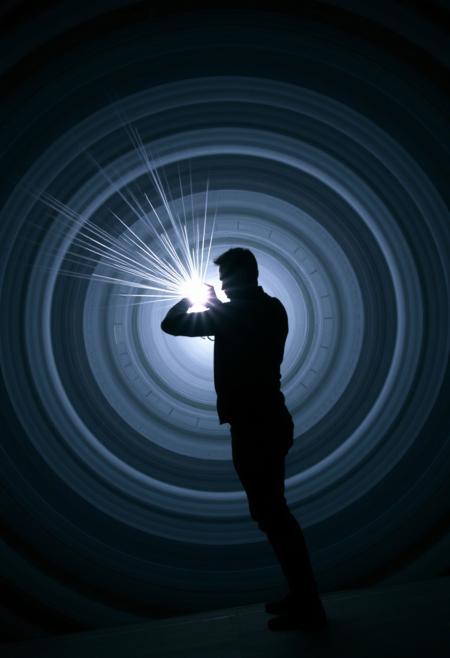A chrome and silver beam hitting a human 100 metres away. The beam is about 1 metre thick and surrounded by multiple concentric grey and white circles of varying diameter. The target is silhouetted and is in an action hero pose