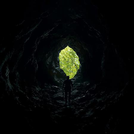 Dark, jagged cave interior with protagonist slowly advancing toward a small opening revealing lush green foliage outside, harsh contrast between shadowy confinement and bright natural world representing hope and escape.