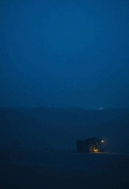 A nostalgic 4K desert scene under a deep königsblau sky — vast dunes cloaked in rich, velvety blue tones. A soft mist clings to the horizon, glowing faintly under the last light. A solitary caravan with faded textiles stands in silence, its lanterns casting cool, diffused reflections on the sand. The wind whispers through distant palm trees. Perfect for a dolly shot — emotional depth, cinematic composition, dreamy textures, One Heart style, ultra-detailed, deep shadows, soft light bloom, melancholic and timeless.foggy