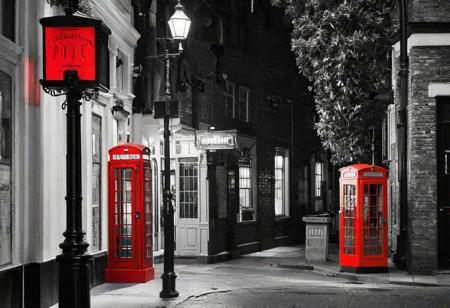 A black and white street corner with a vintage red telephone booth as the sole colorful element. The scene evokes a sense of nostalgia and mystery, reminiscent of classic urban settings.