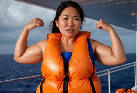 a 35 year old beautiful asian woman with large arms and a big belly, dripping in sweat, wearing a thick orange puffy nylon lifevest, on a cruiseship, tropical, hot, humid, damp, dripping