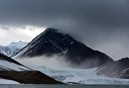 Tibet.  A huge mountain with a snowy peak rises from behind. Black clouds, cloudy, gloomy atmosphere, wind.Black clouds, Transparency, reflections, water, overcast, gloomy atmosphere, wind, ragged fog. The mountain looms over and overwhelms with its gigantic power. A huge avalanche is rushing down from the top., futuristic atmosphere. Perfect Composition,  A masterpiece. An otherworldly atmosphere.