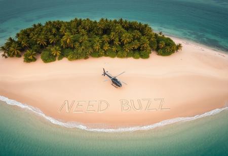 Helicopter aerial view of tropical desert island beach where there is written text on sand by a survivor "NEED BUZZ"