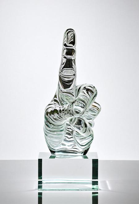 A clear glass sculpture showing the middle finger
