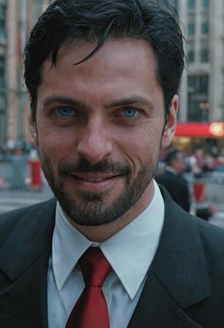 A man with blue eyes, short black hair, small black beard, wearing a black suit with a red tie, in a city center, smiling, semi-closeup, angry face, Matrix scene, the 1990s, film grain, soft lighting, UHD
