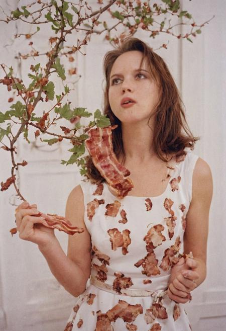 Model photography, the 1990s, bacon, a tree with bacon leaves, beautiful, in a white room, beautiful bacon blossom tree, a female eating bacon, wearing a brown dress, white lighting, film grain, DSLR