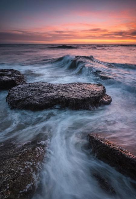 The scene captured by the Sony A7IV with a 20mm G Master lens set at a wide aperture of F1.5 unfolds with haunting beauty, enveloped in a moody and melancholic atmosphereCapture the enchanting beauty of the transition from day to night, known as the blue hour, over a serene ocean with long exposure waves in the style of Michael Shainblum, using a Pentax K-1 Mark II camera with a Pentax D FA 24-70mm f/2.8 ED SDM WR lens. Position yourself to take advantage of the soft, diffused light of the twilight sky as it illuminates the ocean, casting long shadows and creating depth in your image. Experiment with different focal lengths to find the perfect composition, and use a tripod for stability during long exposures. Focus on the interplay of light and shadow, highlighting the rich textures and colors of the ocean under the twilight sky and long exposure waves. Utilize the cool tones of the blue hour to create a moody and atmospheric quality in your image. Post-process your image using techniques such as selective color grading and contrast adjustments to enhance the mood and atmosphere of the scene, creating a captivating and enigmatic photograph that embodies the essence of twilight transcendence with long exposure ocean waves in the style of Michael Shainblum.