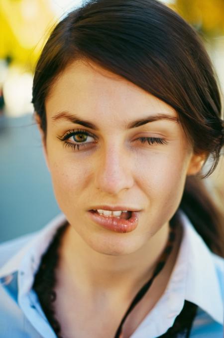 photograph close up portrait of young Turkish woman after office work, open shirt with an open Tie, lovely and Curious look, detailed photograph shot on kodak, bright day in a town, wide angle, 
(<lora:artmakeup_bit_winks_v3:0.9> (biting her lips:1.6) and (winks with one eye at viewer:2), (one eye open and one eye closed))