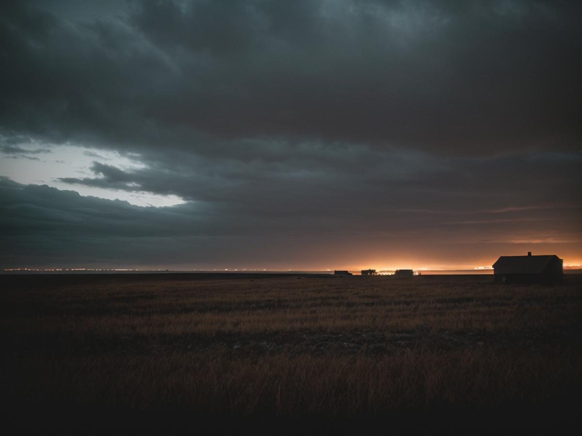 The sky is dark and cloudy with a few faint stars visible, and the sun is setting behind a large field. The field is covered in tall, dry grass, and a house can be seen in the distance. There are also two cars and a truck parked in the field, possibly belonging to the people who live in the house. The overall mood of the scene is serene and peaceful as the day comes to an end.