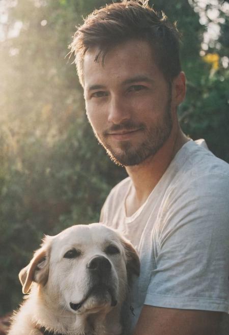 cinematic film still fashion photography portrait of 1man with dog as companion, grainy, headshot, sunlight , Fine Art & Beauty Photography – ,,light diffraction in frame, dreamy,hazy look.  Helios 44-2 lens mounted on a Praktica MTL 5B Helios 44M-4 lens, 58mm f/2,   in a garden. authentic happy smile
