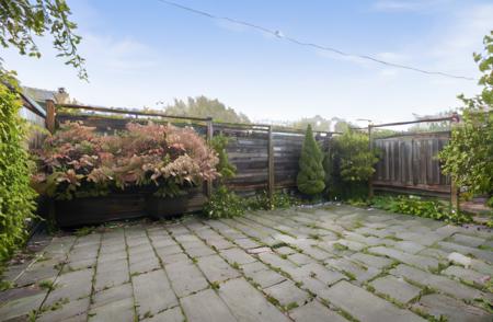 a back garden patio and wooden fence with rose bushes and shrubberies, high res<lora:Grienden_Style:0.7>