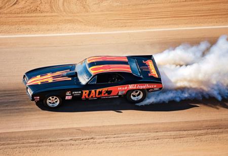 VintageMuscleCar, aerial view, desert, motion blur, 4K, highly detailed, (stylish grainy analog 35mm film photo), ((multiple dragsters race))