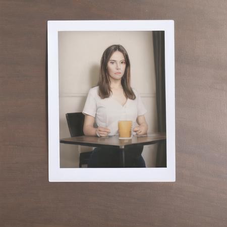 highly realistic adult woman standing up as a glossy polaroid  wooden table background <lora:glossyphotov3-notfullytrained:0.7>