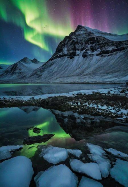 Imagine a breathtaking landscape captured in Iceland, where the ethereal glow of the northern lights dances above a tranquil lake, casting an enchanting reflection on its surface. The majestic silhouette of snow-capped mountains looms in the background, adding to the grandeur of the scene. The camera, a Nikon D850 with a 24mm f/1.4 lens, captures every detail of this awe-inspiring moment with precision. The vivid hues of the aurora borealis shimmer against the darkened sky, creating a mesmerizing display of color and light. In the stillness of the night, the reflection of the northern lights on the lake's mirror-like surface adds an extra layer of magic to this unforgettable vista