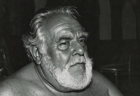 grainy nighttime lowlight photograph, dark room,
masterpiece, 4k, solo, alone, 
tall old hairy tanned grandpa with hairy chest, bullish chubby face with doublechin, face portrait, bushy eyebrows,
father, vater, uncle, onkel, stepdad, stiefvater, grandpa, opa,
gentle charming expression, romantic, intimate, 
sitting in a chair in a dark cloister chapel,