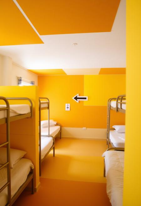 This is one of the dormitories in the hostel, judging by the presence of the
beds.  Noticeably there are no doors or dividers of any kind, therefore no
privacy for the residents.  This could be considered odd, since the room is
obviously intended as a sleeping area.  However, the colors of the walls,
ceiling and floor are sectioned out as blocks - this section is a variety of
yellows.  There is a sign in the shape of an arrow here.