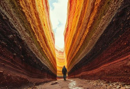 man walking at the bottom of the rainbow cake valley. The valley is made from cake and cream. walking between narrow towering, huge cake and huge topping cream.  canyon of giant layered cake.