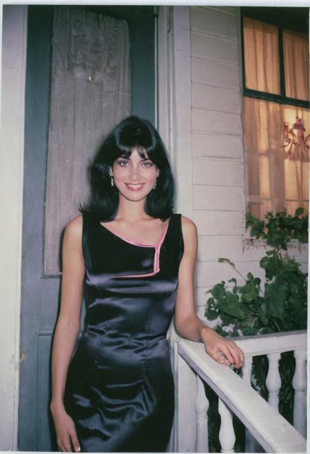 Lifestyle photo, 1980s, a female model, with black hair, straight hair, wearing a fitted black satin dress, outside a home porch, night, pink eyeliner, medium breast, romantic, smiling, posing, polaroid photo, grainy photo, DSLR