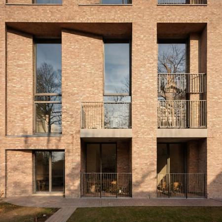 a raw photo of Modern corner residential building with a beige brick facade and a unique design featuring recessed balconies and large, box-like window extensions. Set in a quiet neighborhood with soft evening light accentuating the texture of the bricks. Perspective view. <lora:epi_noiseoffset2:5> <lora:ModernArch_Residence_XL_V1:0.68>