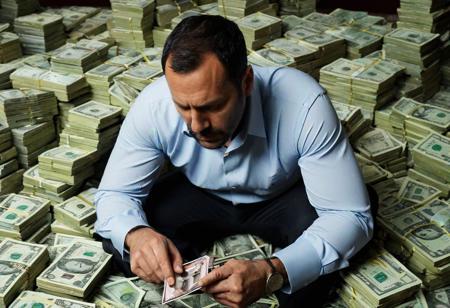 A man, 40 years old, (sad:0.8). Sitting, leaning on a pile of money. (He is looking at a picture frame:2).