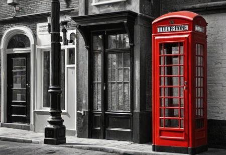 A black and white street corner with a vintage red telephone booth as the sole colorful element. The scene evokes a sense of nostalgia and mystery, reminiscent of classic urban settings. style of Pejac