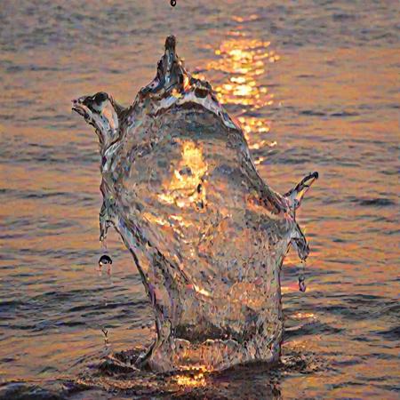 a crystal clear drop of water splashes into the sea,  sunset, macro photography, melting reaction