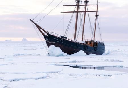 1890s wooden sailing ship caught in the ice in Antarctica, fading light, raised bow, ice crushing bow, the ocean is entirely covered over with ice