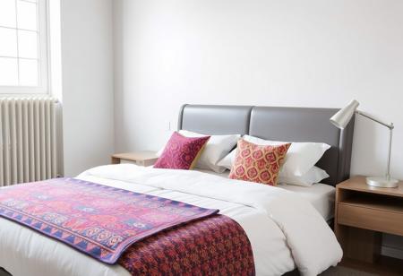 A stylish bed with sleek, contemporary design, adorned with colorful throw pillows and a vibrant patterned blanket in a modern bedroom with brightly painted walls. Next to the bed is a modern nightstand with a minimalist lamp. The space is flooded with natural light.