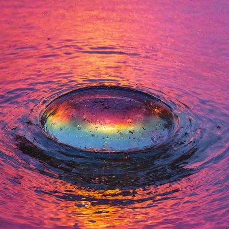 half angle, slightly from the side, warping of time and space, camera lens half way emerging from water, semi submerged rising through the water, with the most beautiful reflection of the colorful sunset, water droplets, refracting colorful light, color burst, explosion, fused, color bomb,