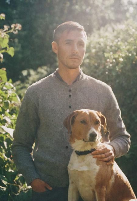 cinematic film still fashion photography portrait of 1man with dog as companion, grainy, headshot, sunlight , Fine Art & Beauty Photography – ,,light diffraction in frame, dreamy,hazy look.  Helios 44-2 lens mounted on a Praktica MTL 5B Helios 44M-4 lens, 58mm f/2,   in a garden.