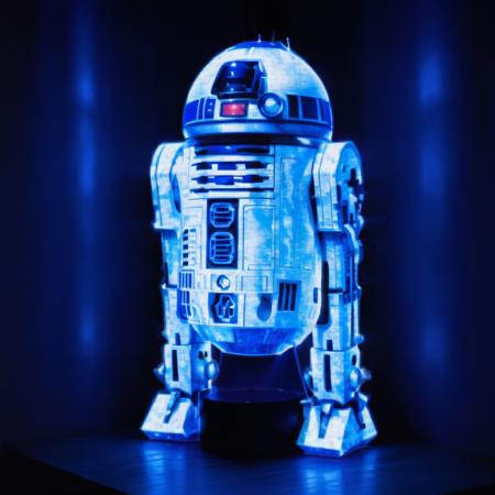 Realistic style 3D hologram projection of R2D2, with vivid and intricate details visible in the holographic representation. The projection emits a soft blue light, casting a glow on the surrounding area. The background is dimly lit to enhance the hologram's visibility, showcasing R2D2's iconic design and patterns in a way that appears tangible and lifelike, as if it's interacting with the real world, <lora:blue_ar:0.8>,blue