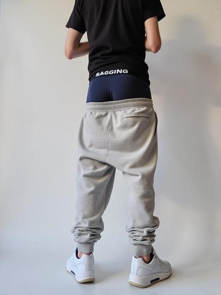 A young man, facing any direction, wearing a sagging light-colored sweatpants, revealing dark-colored boxers with a black waistband and white letters 'SAGGING' 