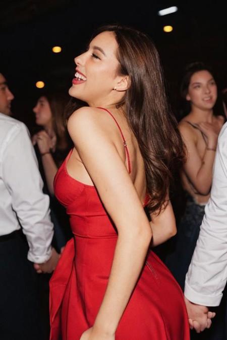 winter postcard, postcard style, white border,  of a close-up portrait featuring a girl in a santa red dress, amidst a bustling dance floor in New York City's vibrant nightlife. Emphasize the sharpness of her face as the crowd dancing around her from behind while she laugh. Use a Nikon F4 camera and analog Kodak Ektachrome slide positive film for a vintage touch