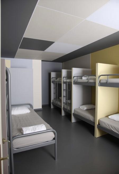 This is one of the dormitories in the hostel, judging by the presence of the beds.  Noticeably there are no doors or dividers of any kind, therefore no privacy for the residents.  This could be considered odd, since the room is obviously intended as a sleeping area.  However, the colors of the walls, ceiling and floor are sectioned out as blocks - this section is a variety of grays.