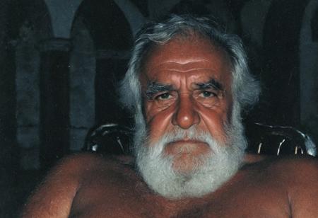 grainy nighttime lowlight photograph, dark room,
masterpiece, 4k, solo, alone, 
tall old hairy tanned grandpa with hairy chest, bullish chubby face with doublechin, face portrait, bushy eyebrows,
father, vater, uncle, onkel, stepdad, stiefvater, grandpa, opa,
gentle charming expression, romantic, intimate, 
sitting in a chair in a dark cloister chapel,