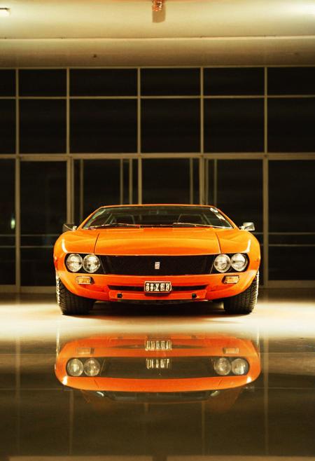analog film photo (Sportscar gleaming orange DeTomaso Mangusta, front view, indoors), white neon lights, (stylish, film grain:1.3) . faded film, desaturated, 35mm photo, grainy, vignette, vintage, Kodachrome, Lomography, stained, highly detailed, found footage