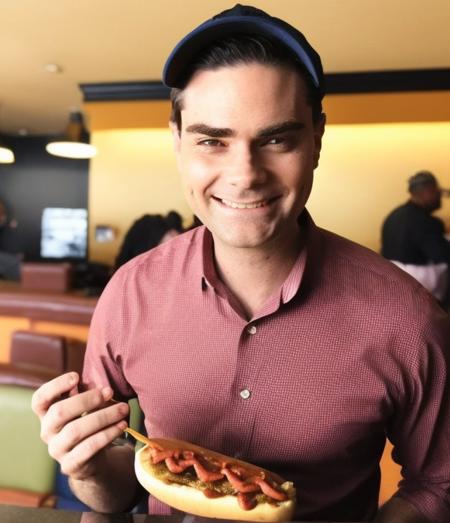 benshapiro person eating a hotdog in the lobby of a motel six. sloppy hotdog with too much ketchup. dressed like a fancy dude man.