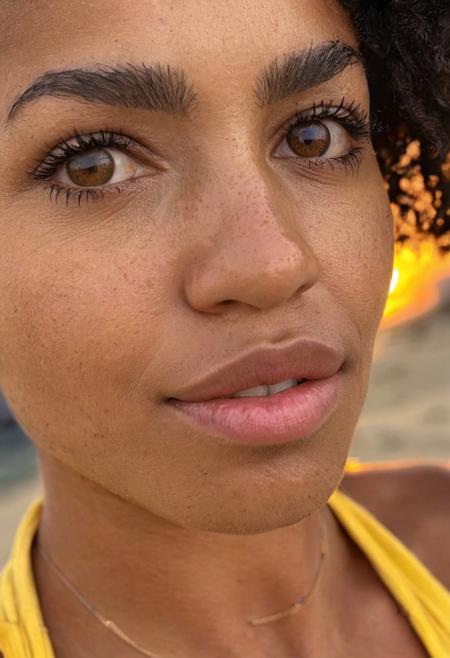 score_9, instagram photo, amateur, skin imperfections, skin pores, skin texture, photo of Zara Nkosi, 27-year-old woman, from South Africa, dark skin, short curly hair, square face-shape, detailed face, deep brown round eyes, detailed eyes, thick eyelashes, full eyebrows, broad nose, wide lips, detailed mouth, prominent cheekbones, strong jawline, 5"9 height, wearing a yellow wrap dress, close-up shot, eye-level angle, leading lines, blurred beach background, vibrant sunset light, shallow depth of field.