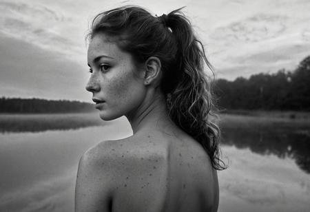 Stunning B&W 35mm photo of a beautiful 20 years old Dutch woman, back to camera, ((full body:1.2)), sexy pose, fully nude, incredibly pretty, looks to die for, narrow nose, fit, highly detailed face, highly detailed skin, freckles, a huge amount of freckles and moles all over body, tiny breasts, perfect breasts, hard nipples, Rounded ass, brown hair, no pubic hair, hairless vagina, big hair, medium hair, 70's style hair, ponytail, brown eyes, perfect eyes, detailed eyes, detailed pupils, the look on her face gives away she is very horny, at a peat lake, dusk, foggy, swirls of mist ,soft natural early morning light, beautiful sky, ultra realistic, realistic skin, detailed skin, realistic vagina, extremely detailed, Rembrandt style light, 8k resolution, masterpiece, 35mm, Hasselblad