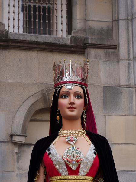 geganta female wearing a crown  in front of a building and a tower in the background <lora:gegants_768-09:1>