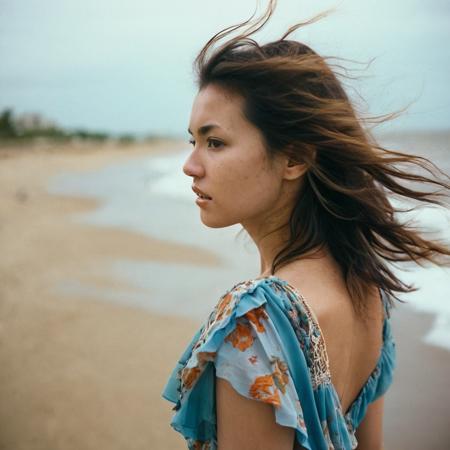 candid photo of M02AWA, windy hair, boho dress, no makeup, close up, from side, looking away, shot with Canon EOS 5D on kodak portra 400, blurry background, on a beach