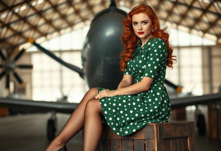 score_9, score_8_up, score_7_up,
RAW, masterpiece, full body, photorealistic, noir_style, 
1girl, beautiful young woman, 30 years old, redhead, long hair, wavy hair,sitting on a wooden crate in an old hangar,
1940's noir, elegant,
Wearing green and white polka-dot 1940s dress with padded shoulders, nylon stockings, low heels.
looking at viewer, 
high details, highly detailed, sharp focus, beautifully detailed woman, detailed eyes and face
wearing 1940s style dress with padded shoulders
detailed background, 1940s airport hangar, 1940s era airplane