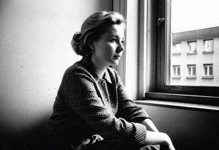german woman 30 years old sitting in front of a window in east berlin in 1962, watching outside, face in shadow, low light, full body shot from side, 1960 soviet look, dark mood, ilford hp5 plus 400, medium format camera,artsy, shadows, wide angle, contact test, damaged print, faded, grainy,blurry, pixelated, motion blur, vignette, high contrast
