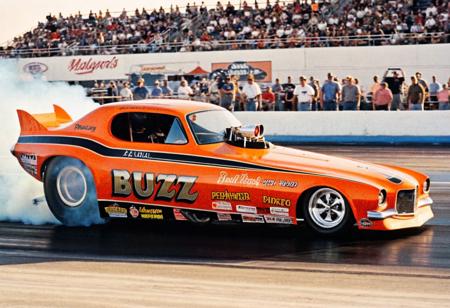 ClassicMuscleCar, orange dragster, side view, sunny, race track, people, smoke trail, 4K, highly detailed, (stylish grainy analog 35mm film photo, "BUZZ")