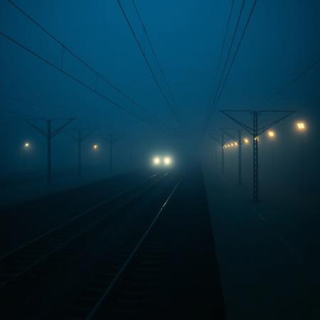 "A still, hauntingly beautiful evening train station, bathed in deep blue hues and thick, slow-moving fog. The camera lingers motionless above the tracks, capturing the eerie stillness—only the faint glow of distant station lights piercing the mist. Suddenly, a slow, ghostly movement: a single train arrives silently, its headlights cutting through the fog like dim searchlights. The air shimmers with floating particles, and the scene feels frozen in time, yet alive with tension. No people, no loud sounds—just the quiet hum of machinery and the occasional creak of metal. Cinematic, 4K, 35mm film grain, muted colors, surreal and dreamlike."