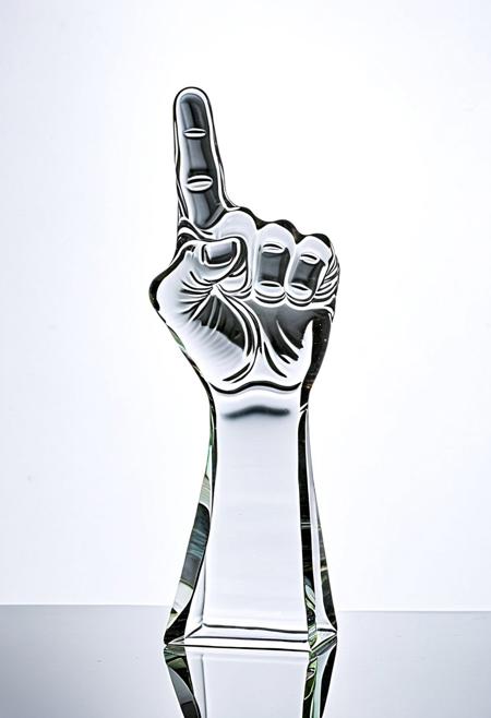 A clear glass sculpture of a raised fist showing the middle finger