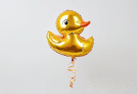 Shiny foil helium balloon in the shape of a duckling, with a sunny yellow and orange color palette, set against a white background
