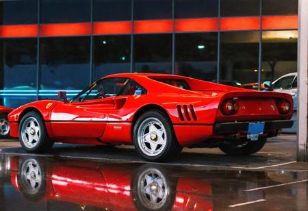 analog film photo (Sportscar, gleaming red Ferrari 288, rear side view, indoors, dark parking lot, neon lights, reflections, night), (film grain:1.3) . faded film, desaturated, 35mm photo, grainy, vignette, vintage, Kodachrome, Lomography, stained, highly detailed, found footage