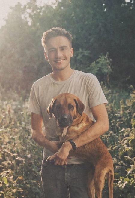 cinematic film still fashion photography portrait of 1man with dog as companion, grainy, headshot, sunlight , Fine Art & Beauty Photography – ,,light diffraction in frame, dreamy,hazy look.  Helios 44-2 lens mounted on a Praktica MTL 5B Helios 44M-4 lens, 58mm f/2,   in a garden. authentic happy smile