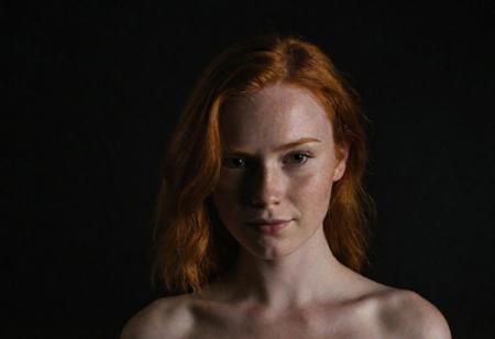 Close-up, (A beautiful ginger girl, giant breasts), grim smile, relaxed pose, portrait movie shot, serious, menacing, chiaroscuro style photo, dark background, minimalism, dramatic lighting, professional quality, dull highlights and shadows, natural and   original,